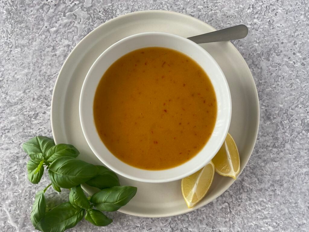 Bowl of creamy lentil soup served with fresh basil and lemon wedges