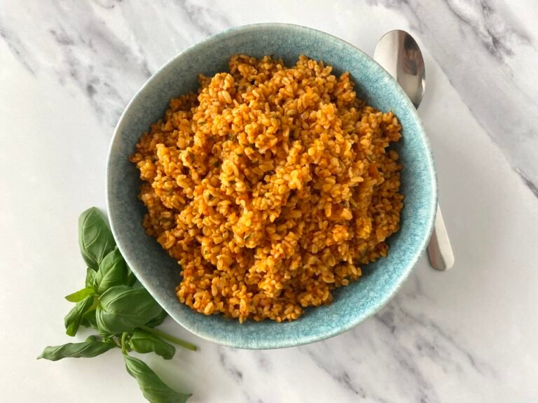 Bowl of tomato and bulgur pilaf served with fresh basil leaves