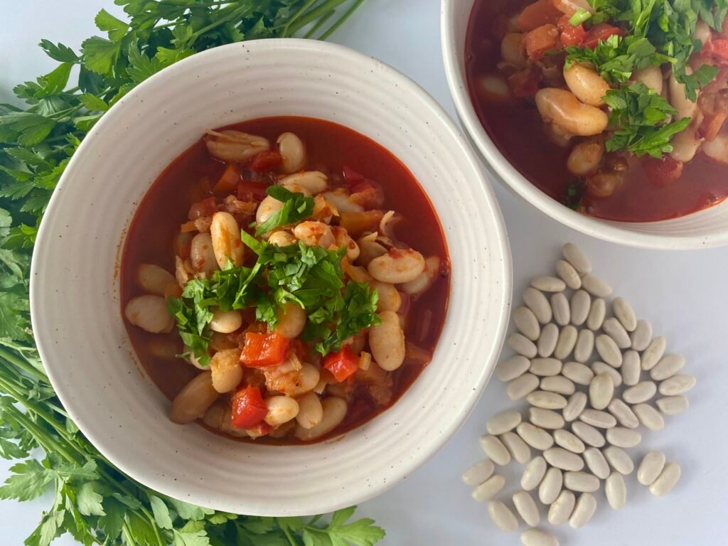 Bowls of vegan white bean stew served with fresh parsley