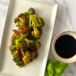 Pan-fried soy broccoli served with fresh basil leaves and soy sauce