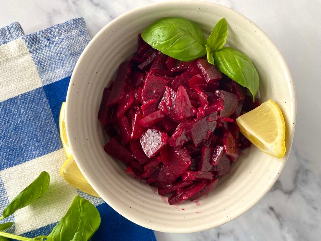 Beetroot and garlic salad served with basil leaves and lemon wedges