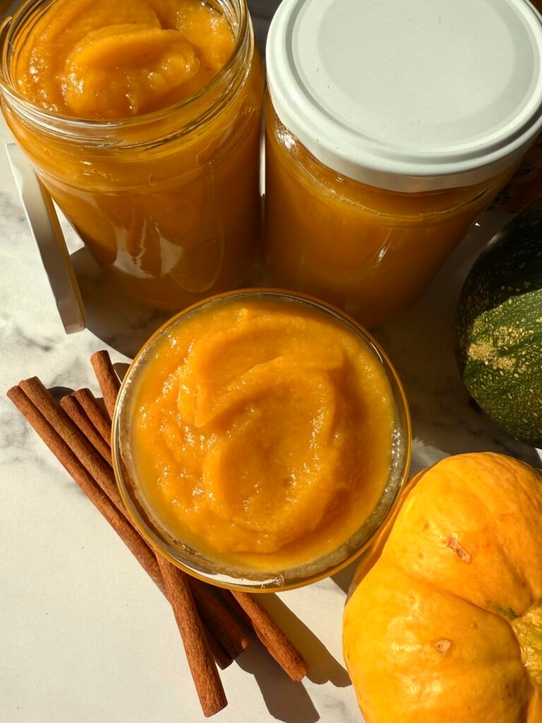 Homemade pumpkin puree in a glass jar, surrounded by fresh pumpkin slices and cinnamon sticks. The puree is smooth and creamy, perfect for baking pies, soups, and fall-inspired dishes. Easy step-by-step pumpkin puree recipe for home cooking enthusiasts and seasonal bakers.