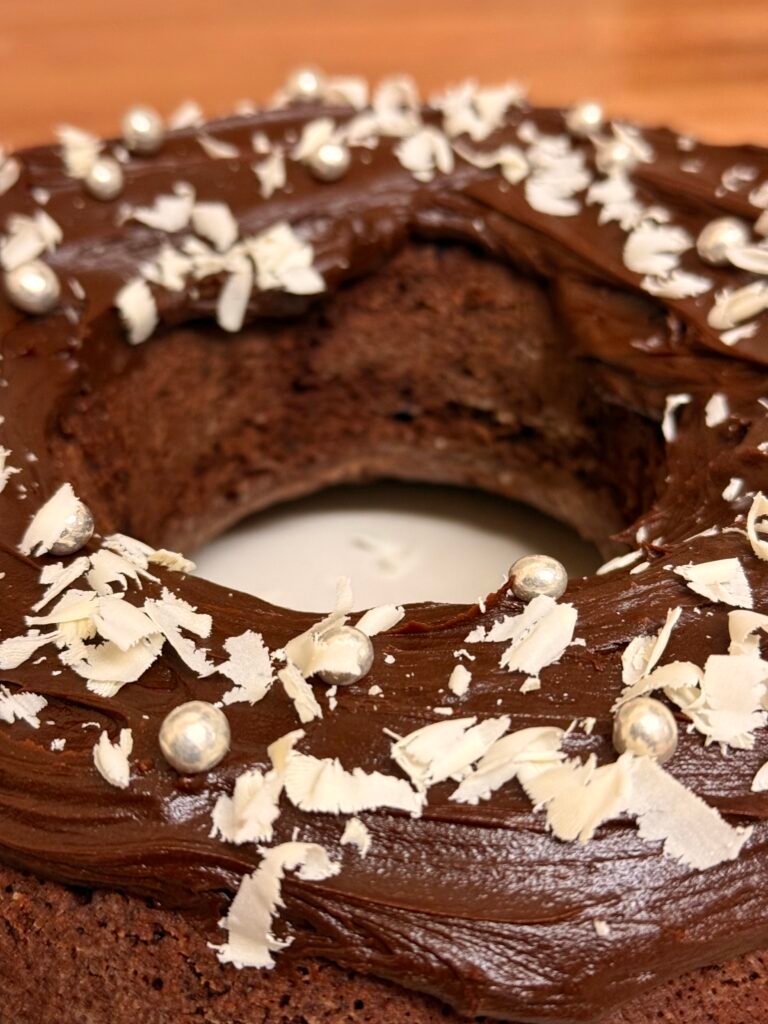 A close-up of the chocolate bundt cake showcasing its shiny ganache coating and scattered white chocolate shavings.