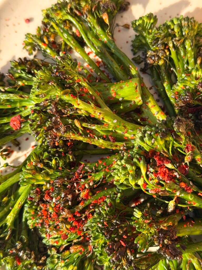 Close-up shot of charred broccoli florets with crispy edges and bright lemon slices.