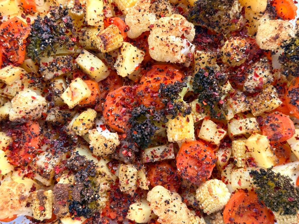 Golden spiced roasted vegetable medley with carrots, potatoes, broccoli, cauliflower and baby corn on a tray